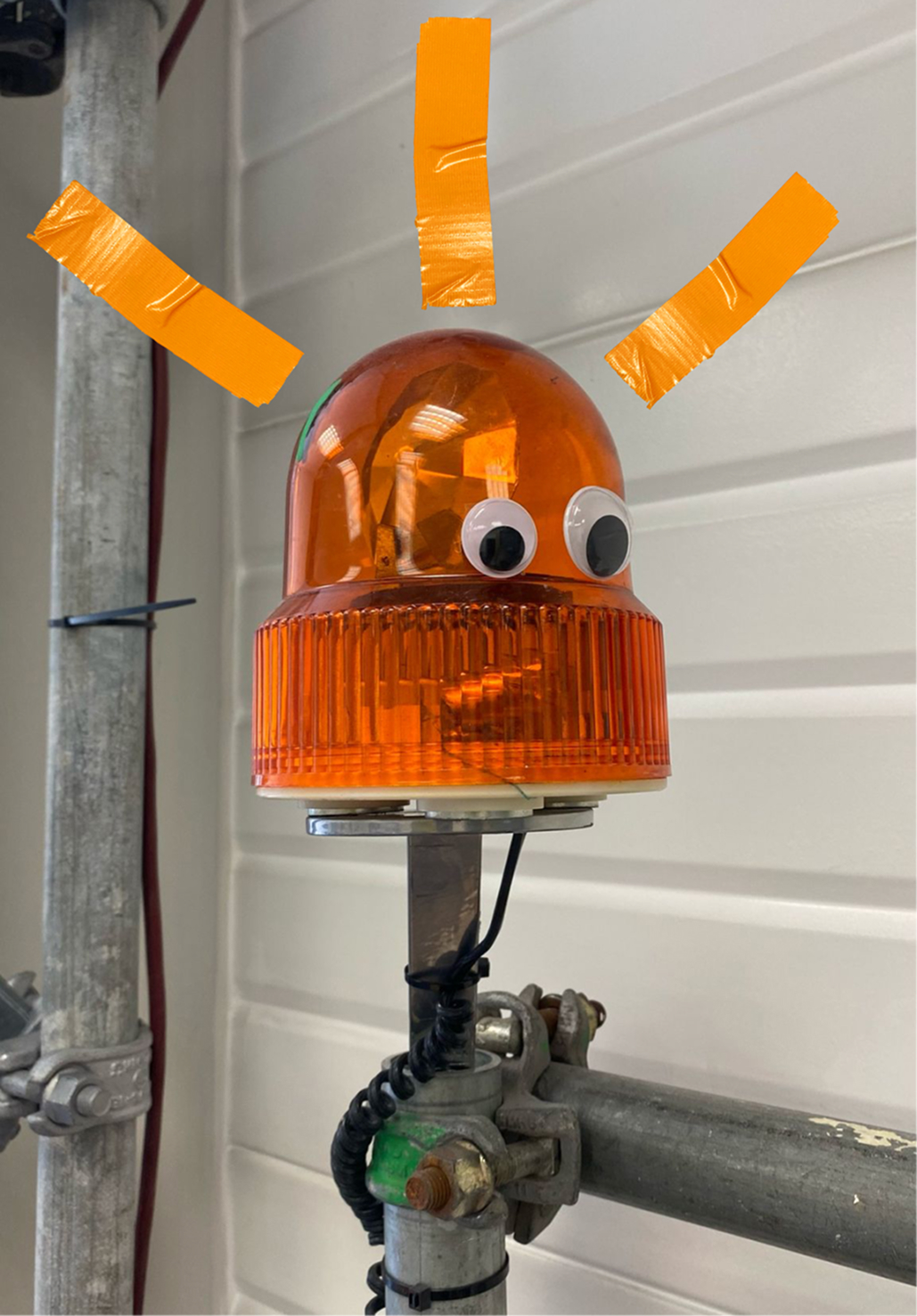 Orangene Warnlampe mit Wackelaugen beklebt